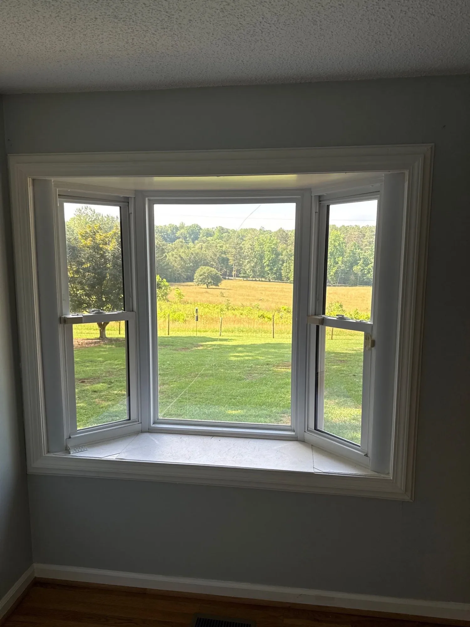 Bay window with painted trim in an empty room looking out over a field